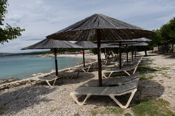 Sunshades sun loungers for rent on the beach , empty Punat beach on the island of KRK