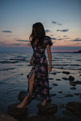 Woman in dress standing near the lake at evening