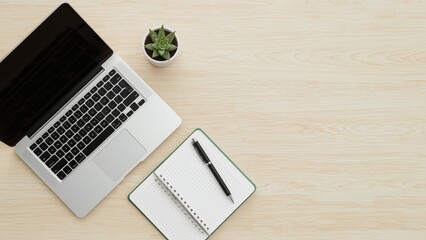 A modern workspace featuring a laptop, notepad, and green plant, creating a minimalist and inviting study environment.
