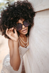 Portrait of a woman with afro hair and sunglasses smiling and happy - Modern fashion and style concept.