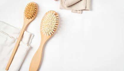 Wooden hairbrushes on white background with towels and fabric  