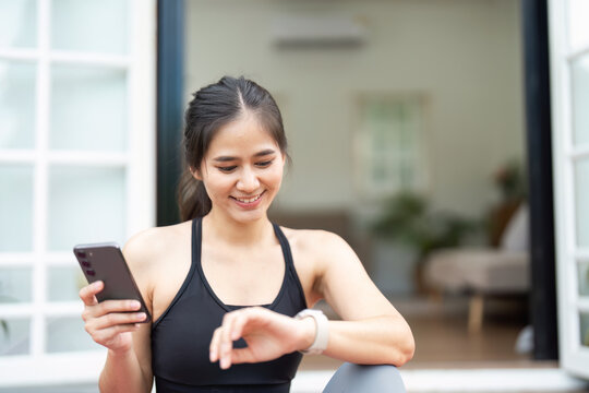 Fitness Tracking. Young woman checking her smartwatch while sitting on yoga mat.
