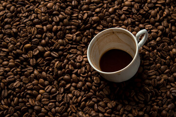 A cup of coffee drunk on coffee beans. Freshly roasted coffee beans