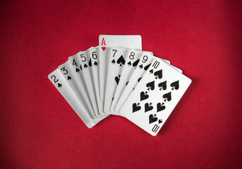 A deck of cards is displayed on a rich red surface, highlighting the numbers and the ace of hearts....