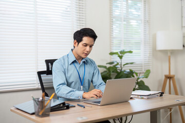 Fototapeta premium Focused Male Professional Working on Laptop at Desk