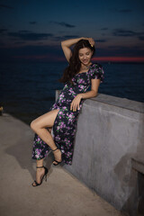 Woman in dress posing at pier near sea at the evening