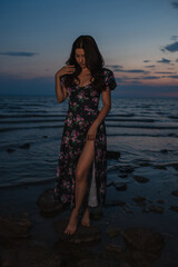 Woman in dress standing near the lake at evening