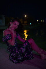 Woman in red light sitting at the night pier