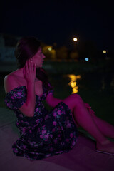 Woman in red light sitting at the night pier