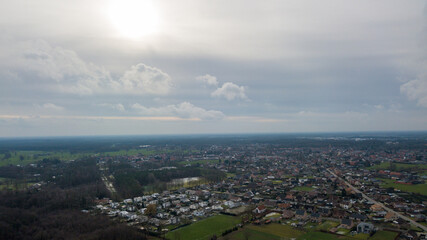 An absolutely stunning aerial photograph captures a serene town surrounded by lush green fields beneath a cloudy sky