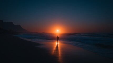 A person standing alone on the beach watching a stunning sunset over the ocean at dusk.