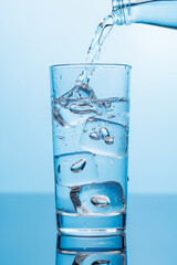 Crystal clear water being poured into a transparent glass, creating refreshing ripples and bubbles