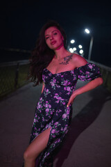Woman in red light posing at the night pier