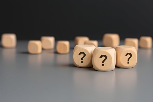 Wooden Dice with Question Marks Displayed on a Gray Surface
