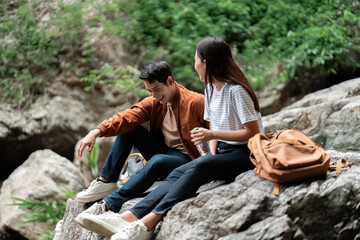 Hiking Break. Young couple resting on rocks during a nature hike, enjoying each other's company.