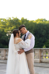 The bride in a white dress and a veil laid her hands on the shoulders of the groom and contacted...