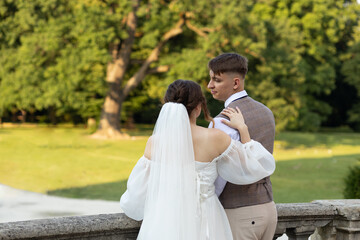 Photo of the bride and groom from the side in the park.The parapet of the castle, who has a bride...