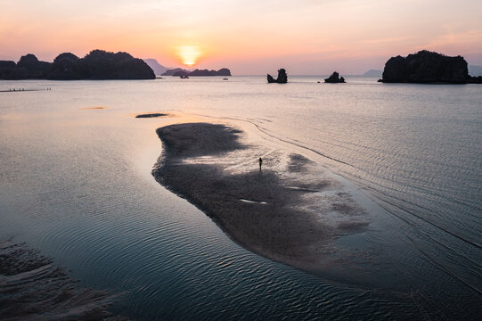 Aerial view of woman in bikini walking on a sandbar at sunset, Malaysia