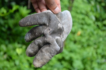 Used hand gloves with torn surfaces held in the hand. Protective industrial work gloves