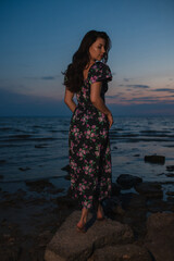 Woman in dress standing near the lake at evening