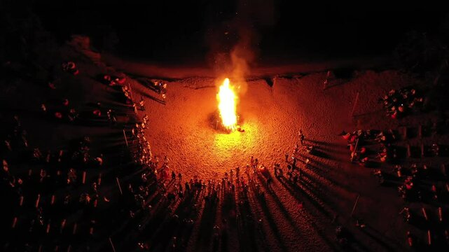 people standing around a burning fire in the dark