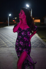 Woman in red light posing at the night pier