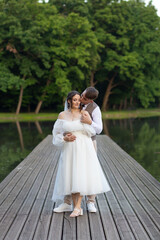 bride and groom on the bridge. The groom kisses the bride on the cheek, standing behind her. The...