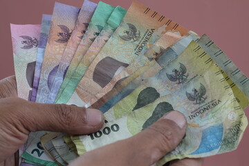 A man holds Indonesia Rupiah (IDR) money in his hand and counts them. close-up view on a isolated background.
