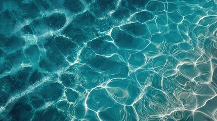 A mesmerizing, top-down view of turquoise water, with sunlight creating intricate, shimmering patterns on its clear surface