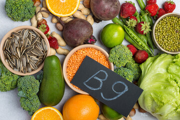 Top view of foods rich in vitamin B9 (folic acid) with vegetables, legumes, fruits and seeds. Healthy lifestyle and nutrition concept on light background.