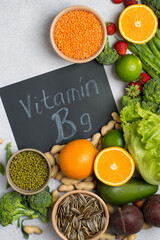 Flat lay of natural plant foods high in folate (vitamin B9) including broccoli, beetroot, oranges, lentils, peanuts, green peas and leafy greens.
