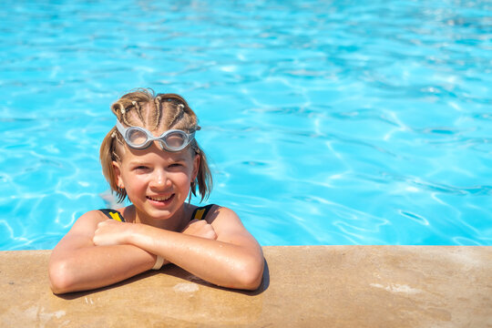 Portrait smiling girl in swimming pool, child in swimming glasses. Summer travel hotel vacation or classes. Kid relaxing in pool. Childgirl swimming in blue water. activity, watersports.