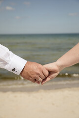 Verliebtes Brautpaar hält sich an den Händen – Detailaufnahme einer Strandhochzeit