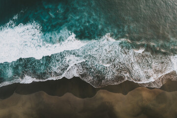 Fototapeta premium Vues aériennes spectaculaires de vagues s’écrasant sur le sable noir d’une plage tropicale à La Réunion.