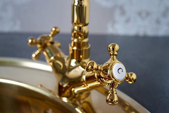 Deck mounted one hole gooseneck kitchen faucet with four spoke handles. Luxury kitchen detailing close up selective focus shot.