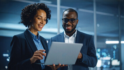 Two individuals, a man and woman, collaborating intently over a laptop, showcasing a scene of modern business interaction within an office environment