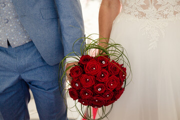 Brautpaar hält traditionellen Brautsrauss mit roten Rosen und Perlen