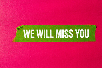We will miss you message written on ripped torn green paper tape on pink background. Conceptual we...