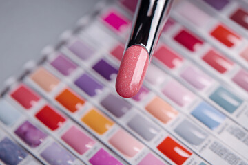 Colorful nail polish selection displayed with a glittery pink shade in focus on a swatch chart from a nail salon