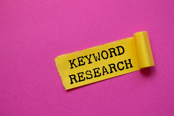 Keyword research message written on ripped torn yellow paper piece on pink background. Conceptual keyword research symbol. Copy space.