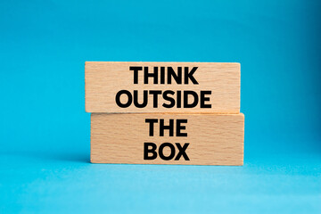 Think outside the box message written on wooden blocks on blue background. Conceptual think outside...