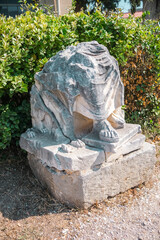 Ancient broken statue base with roman feet and draped stone garment in Corinth
