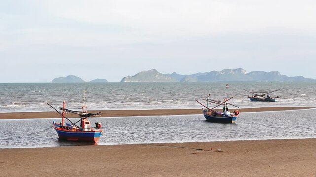 Ancored thai fishing boats at low tide representing seafood trade, tourism, and local fishermen's livelihood