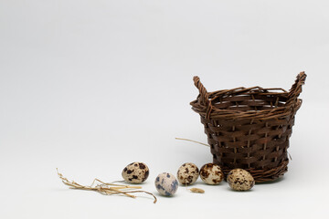 Quail eggs and wicker basket on white background