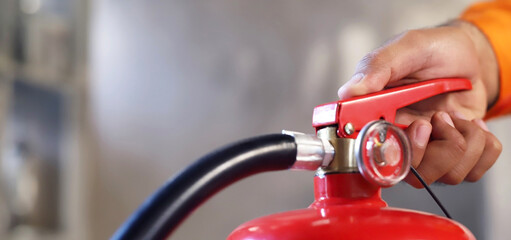 Closeup of a male Hand Using Fire Extinguisher to Extinguish Fire  available in emergencies...