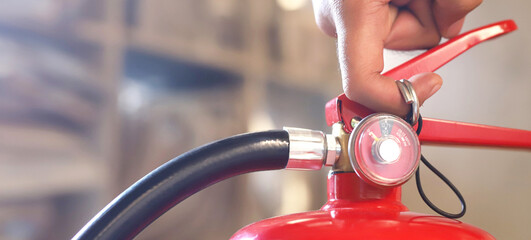 Closeup of a male hand pulling the safety pin of a manual chemical Fire extinguisher available in...