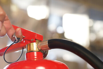Closeup of a male hand pulling the safety pin of a manual chemical Fire extinguisher available in...