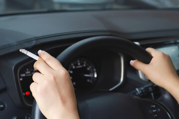 close up woman hand hold smoking a cigarette in car while driving travel. healthy lifestyle. or No smoking campaign Concept.