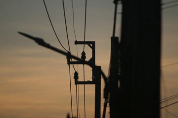Electrical Pole Silhouette at Sunset:  A close-up silhouette of an electrical pole and its...