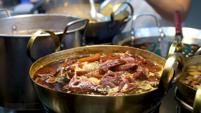 Slow motion view of Ostri, traditional Georgian stew served in rustic clay bowl. Bubbling dish is garnished with fresh herbs and onions, emphasizing its authentic appeal. Bowling Ostri from stove